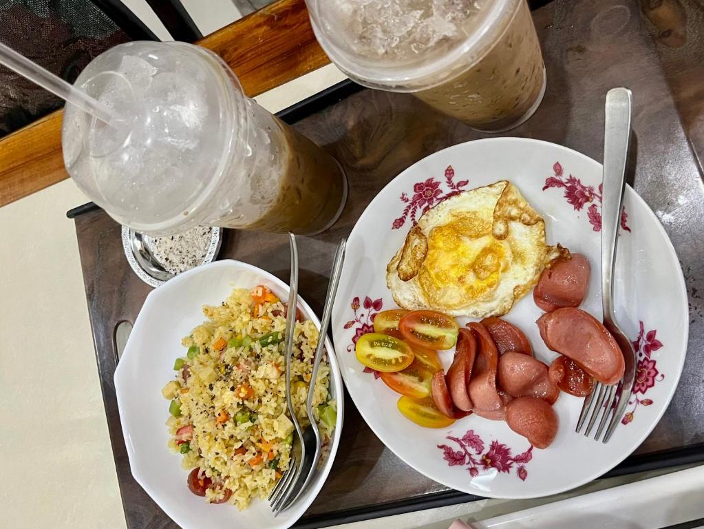 taca z dwoma talerzami jedzenia z jajkami, kiełbasą i ryżem w obiekcie Cherry Homestay - Hoàng Đế motel w mieście Châu Đốc
