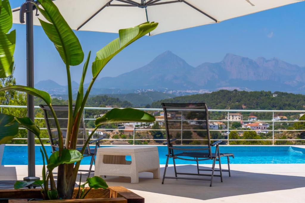 a patio with chairs and a plant and a pool at Villa Mimosas in Altea