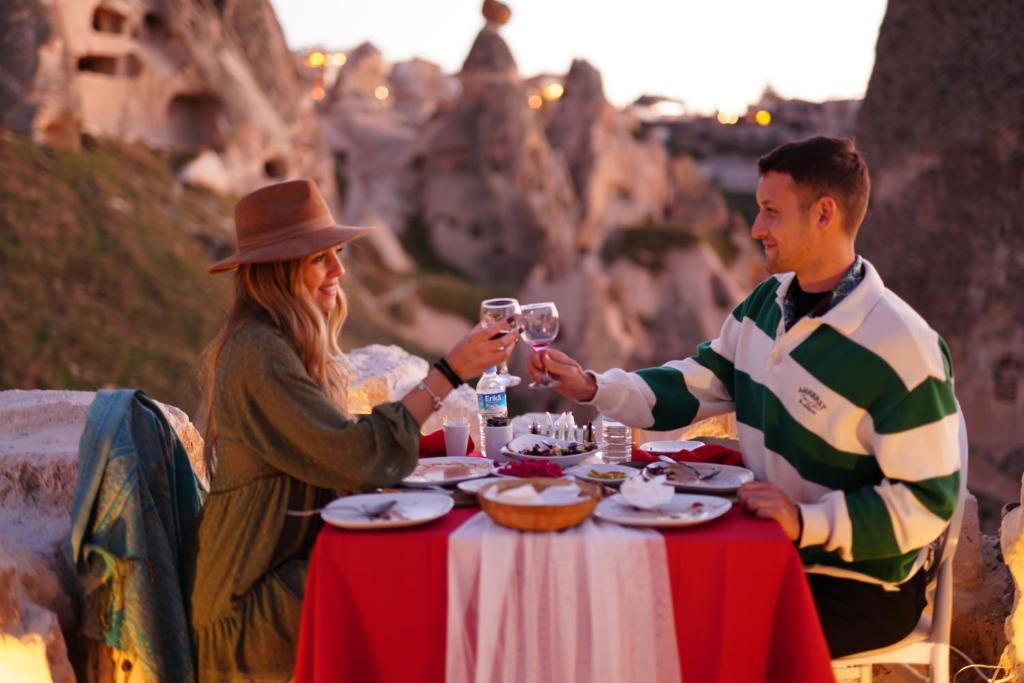 a man and woman sitting at a table with wine glasses at Anatelein Boutique Cave Hotel in Uchisar