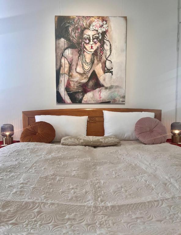 a bedroom with a bed with a painting on the wall at LUXUS sApartments in der Kunstvilla &amp; kostenloses parken in Premstätten