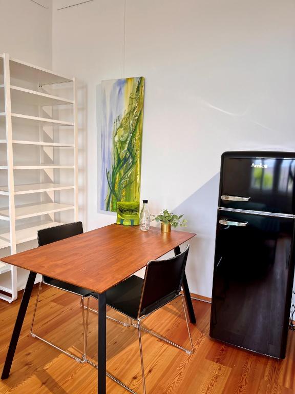 a dining room table with two chairs and a refrigerator at LUXUS sApartments in der Kunstvilla &amp; kostenloses parken in Premstätten