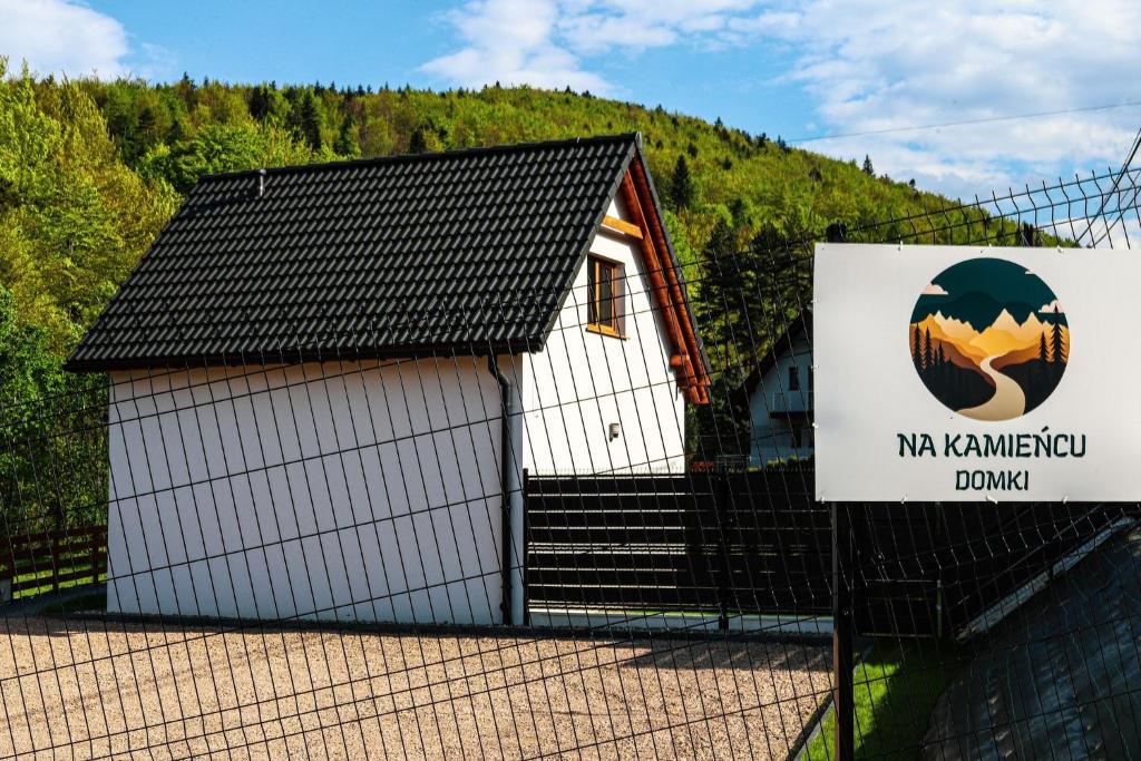 a small white building with a sign in front of it at Na Kamieńcu domki in Rzyki