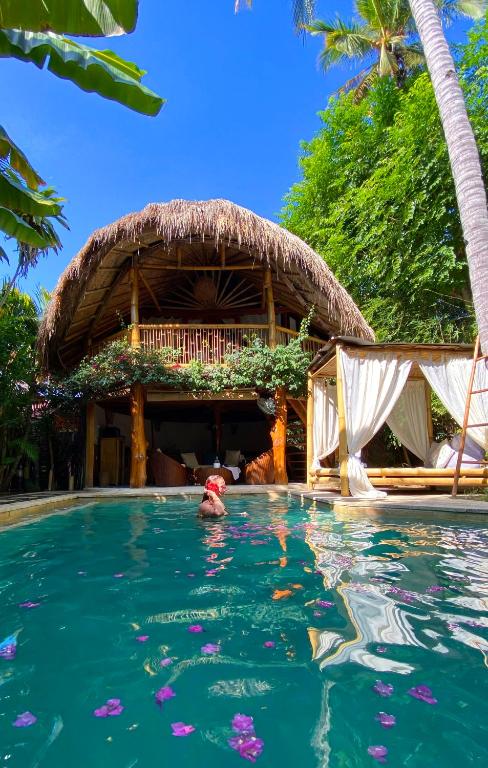 una persona en el agua en una piscina frente a un resort en Meno Island Villas, en Gili Meno