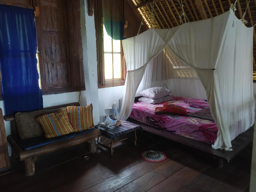 sypialnia z łóżkiem z moskitierą w obiekcie Villa Watumita Sikka w mieście Hitokalak