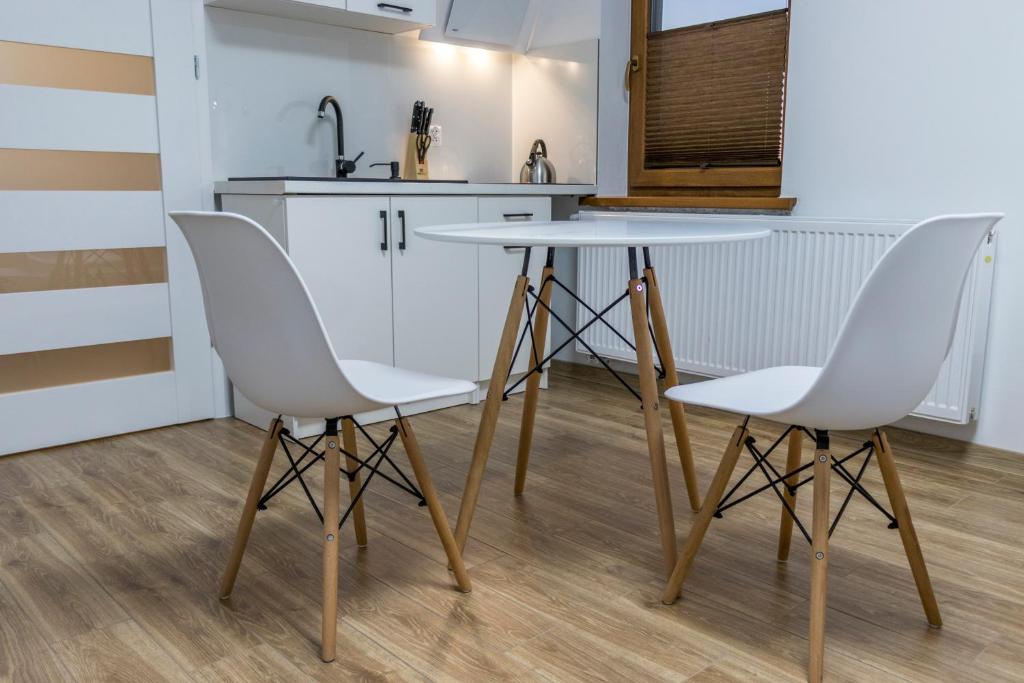 a kitchen with two white chairs and a table at Apartamenty przy szlaku in Krajno Pierwsze