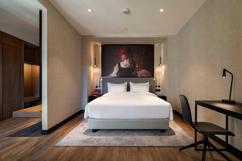 a bedroom with a bed and a painting on the wall at Radisson RED Tbilisi in Tbilisi City