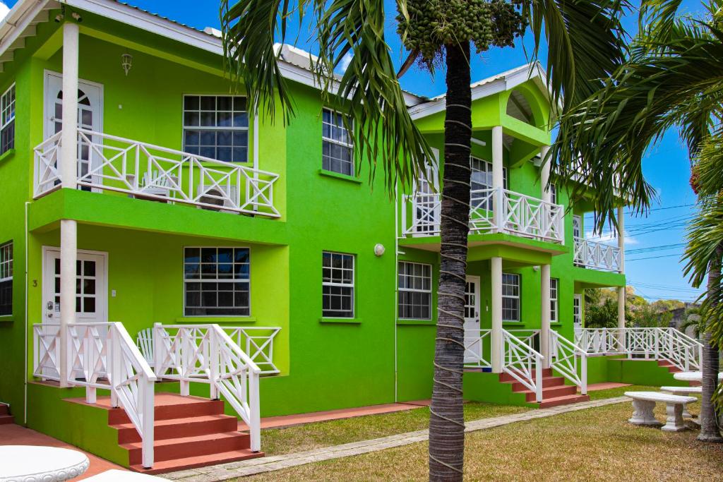a green building with palm trees in front of it at Best E Villas Prospect St James in Saint James