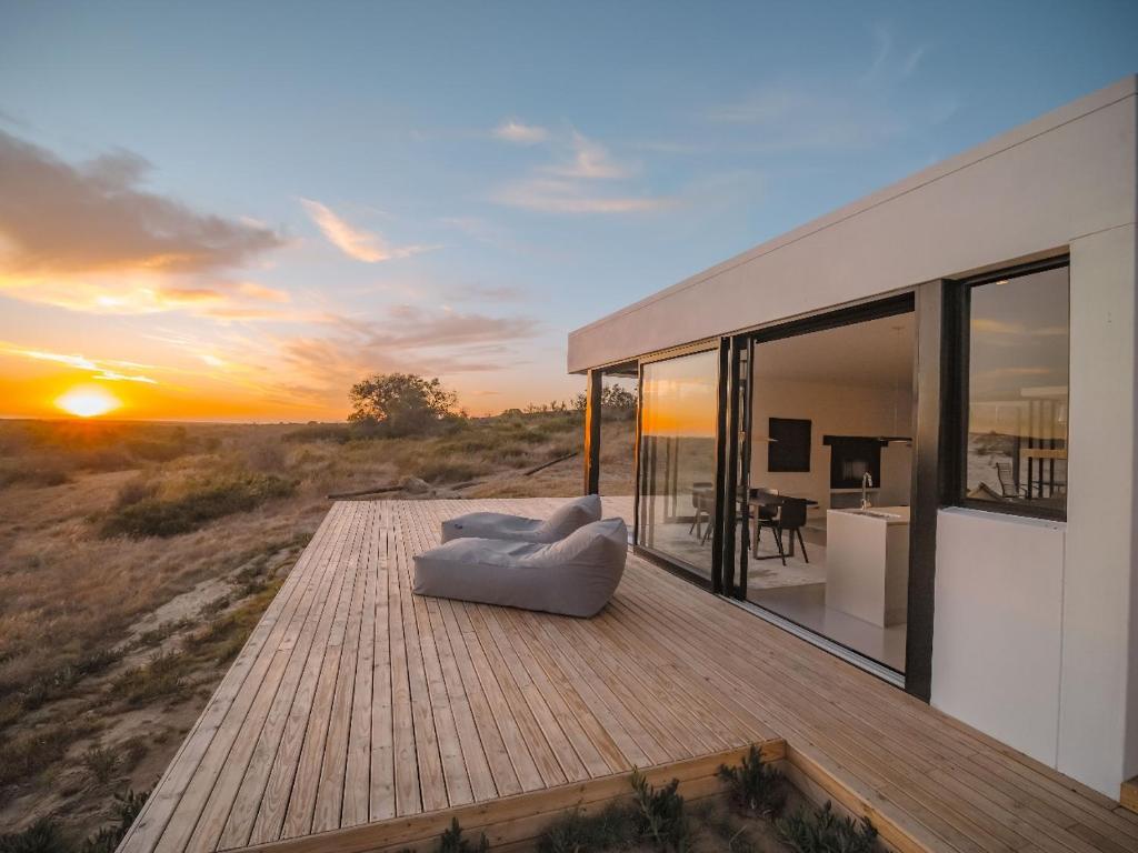 une maison avec un canapé sur une terrasse avec vue sur le coucher du soleil dans l'établissement Rondeberg Farms, à Darling