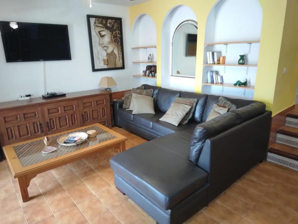 a living room with a black leather couch and a table at Lamedos in San Luis de Sabinillas