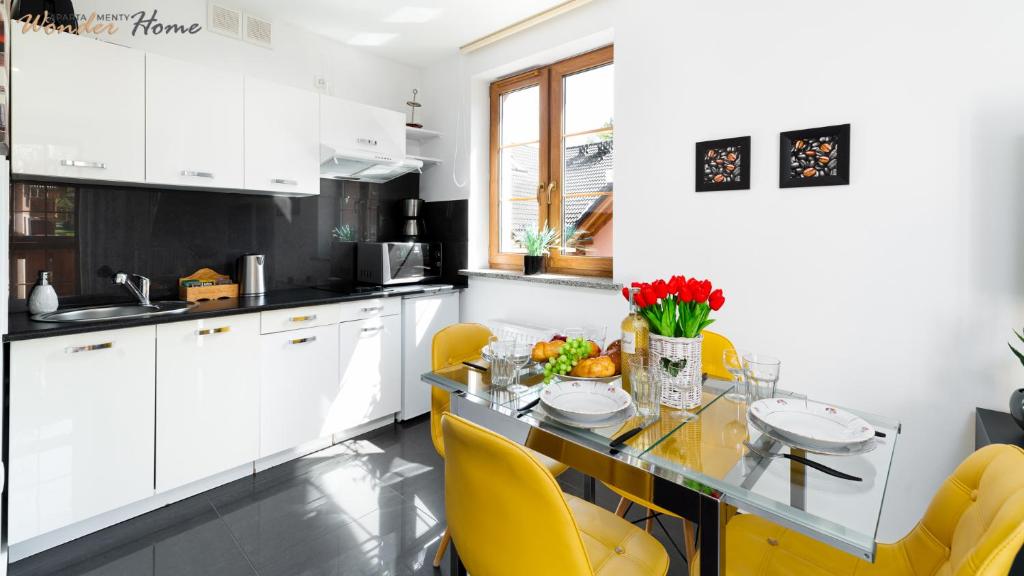 カルパチにあるWonder Home - Apartamenty z balkonami Leśny Dom II - w cichej i zielonej części Karpaczaのガラステーブルと黄色の椅子付きのキッチン