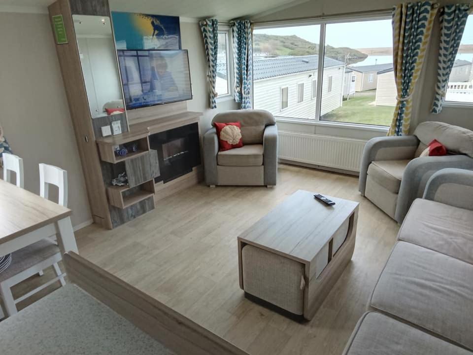 a living room with a couch and a table at Spacious Comfortable Surf Shack Caravan 35 x 12ft with Sea View Haven Littlesea Weymouth in Weymouth