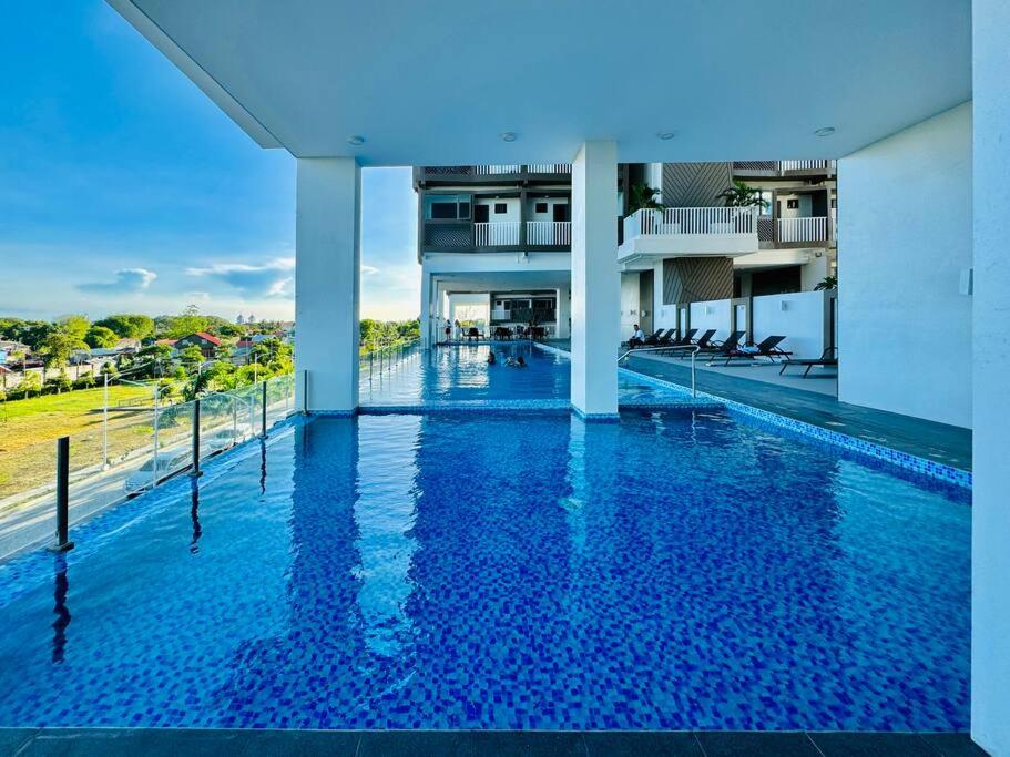 a large swimming pool in a building with blue water at WV 10 Stylish 1BR Apartment in Iloilo City