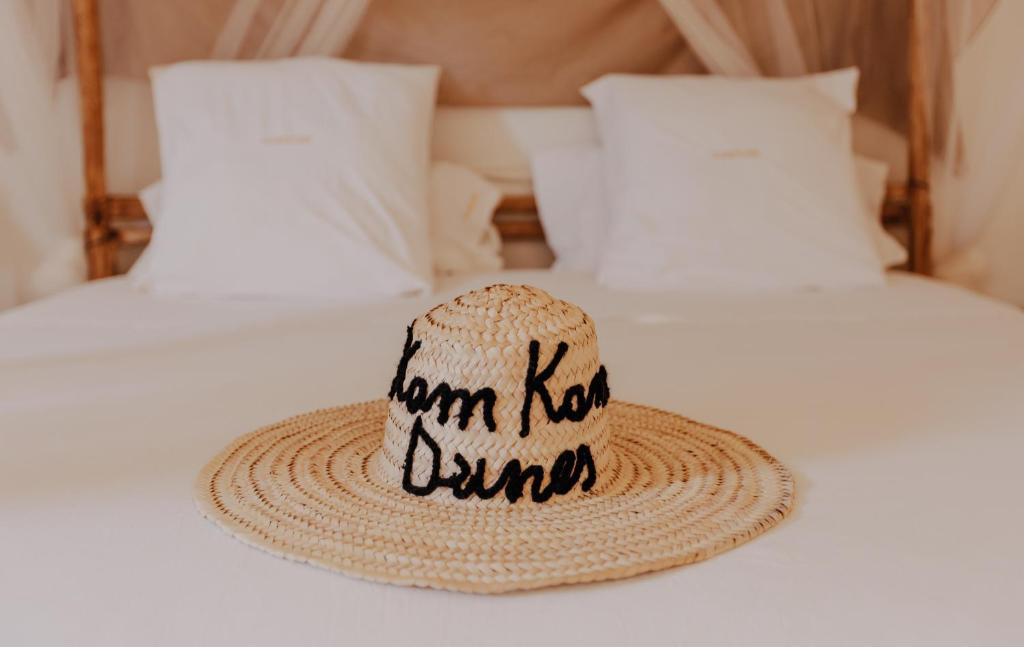 un sombrero de paja sentado en la parte superior de una cama en Kam Kam Dunes, en Merzouga