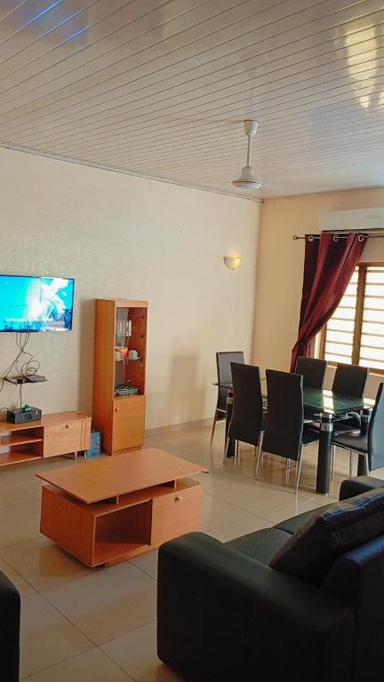 sala de estar con TV, mesa y sillas en Charly chic-agla en Cotonú