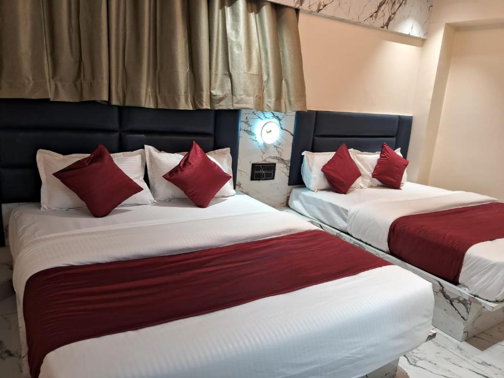 two beds in a room with red and white pillows at HotelMeetPalace in Ahmedabad