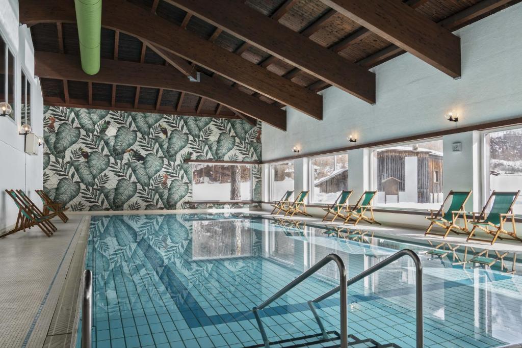 a large swimming pool with chairs and tables at Bad Serneus Water Resort in Klosters