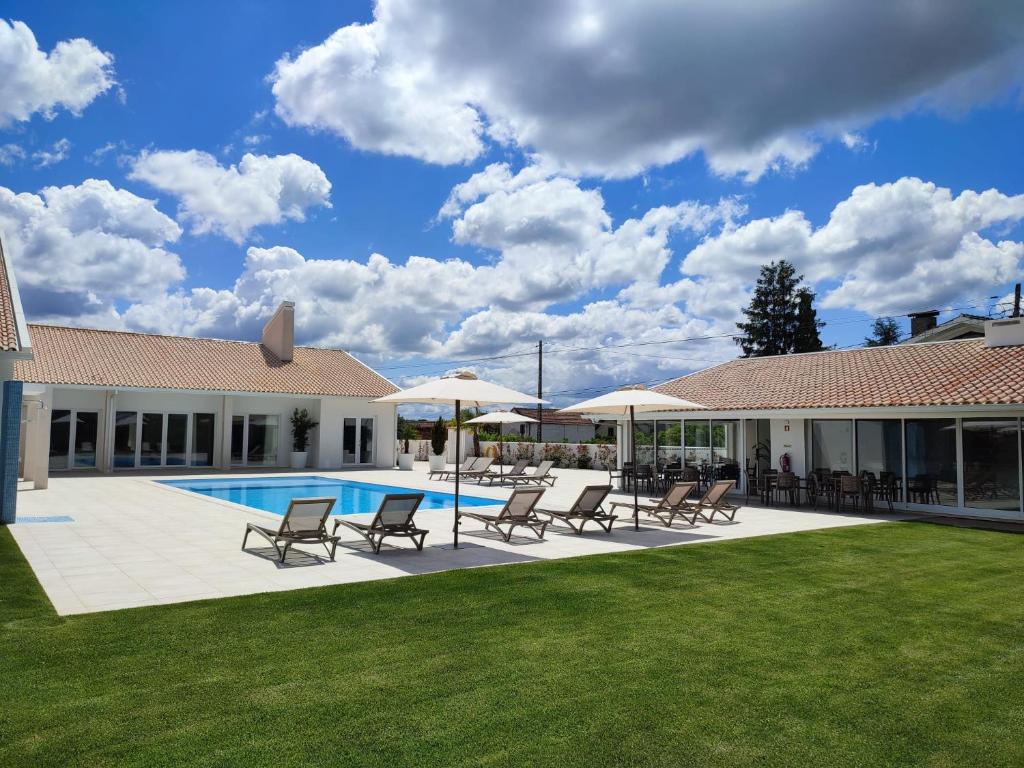 梅阿利亞達的住宿－NR Suites，庭院内一个带椅子和遮阳伞的游泳池