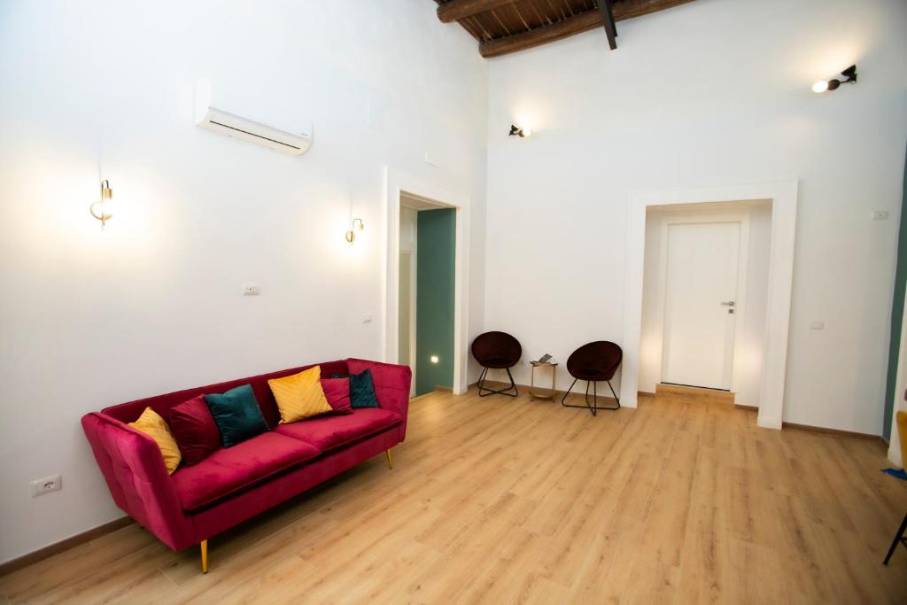 ein Wohnzimmer mit einem roten Sofa und 2 Stühlen in der Unterkunft Palazzo Goyze in Neapel
