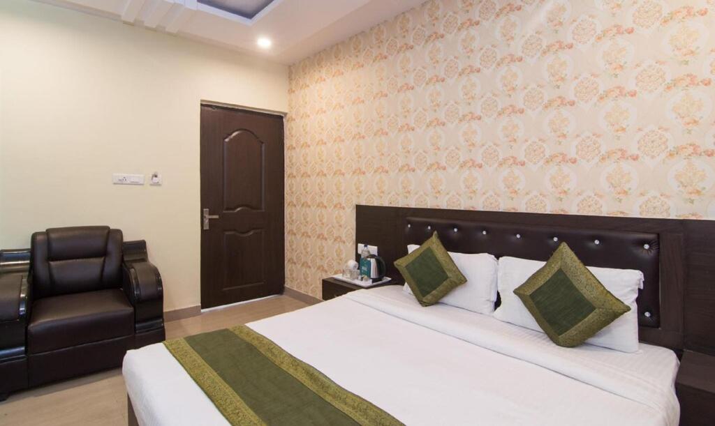 a hotel room with a bed and a chair at Hotel Pacific Blu in Lucknow