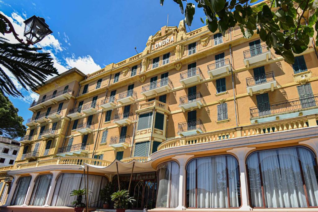 un gran edificio amarillo con ventanas en una calle en Grand Hotel De Londres en San Remo