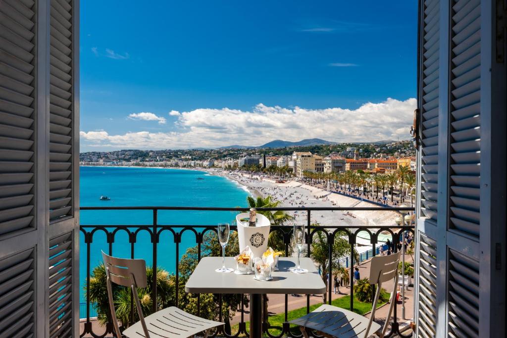 einen Balkon mit einem Tisch und Strandblick in der Unterkunft Hotel Suisse in Nizza