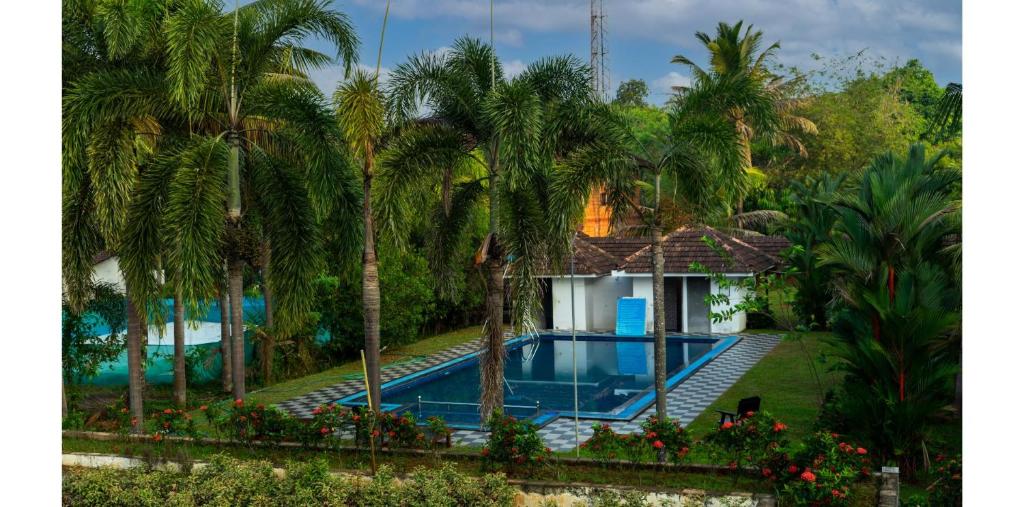 a pool in front of a house with palm trees at Kumarakom Heritage Resort & Ayurveda in Alleppey