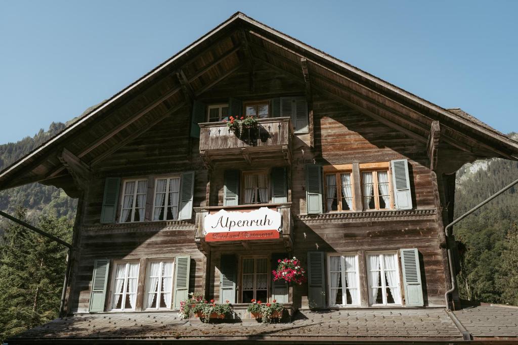 - une grande maison en bois avec un panneau dans l'établissement Alpenruh Kiental, à Griesalp
