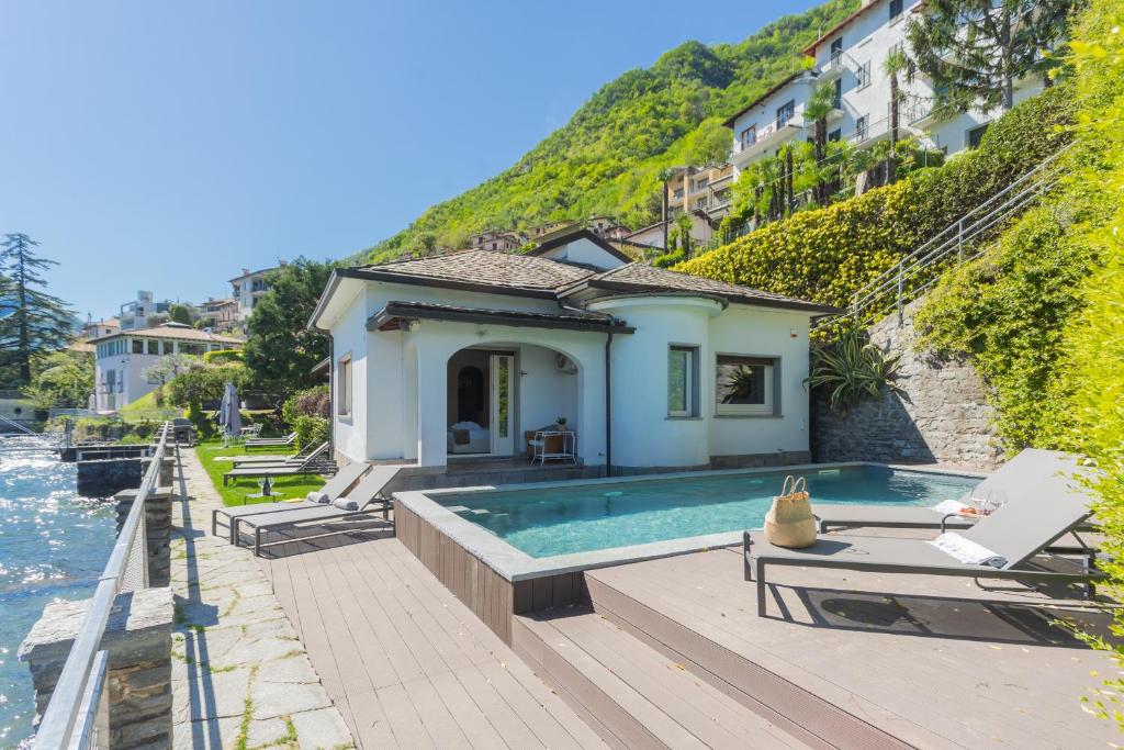 a house with a swimming pool next to the water at Villa Bianca - Front Lake Pool by Rent All Como in Sala Comacina