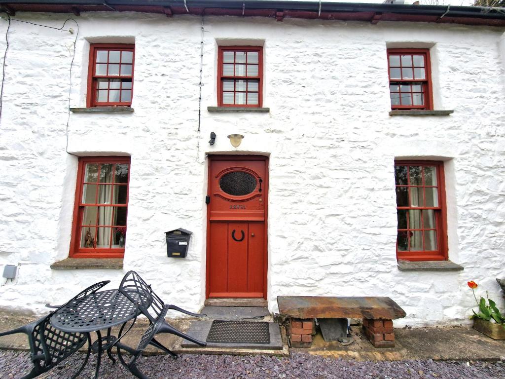 a red door on a white building with a bench at Arwel Nanternis in Llanllwchaiarn