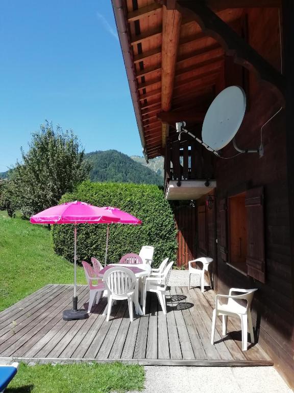 une terrasse avec une table, des chaises et un parasol dans l'établissement Chalet 3 Etoiles - Le pèlouêt, à Morzine