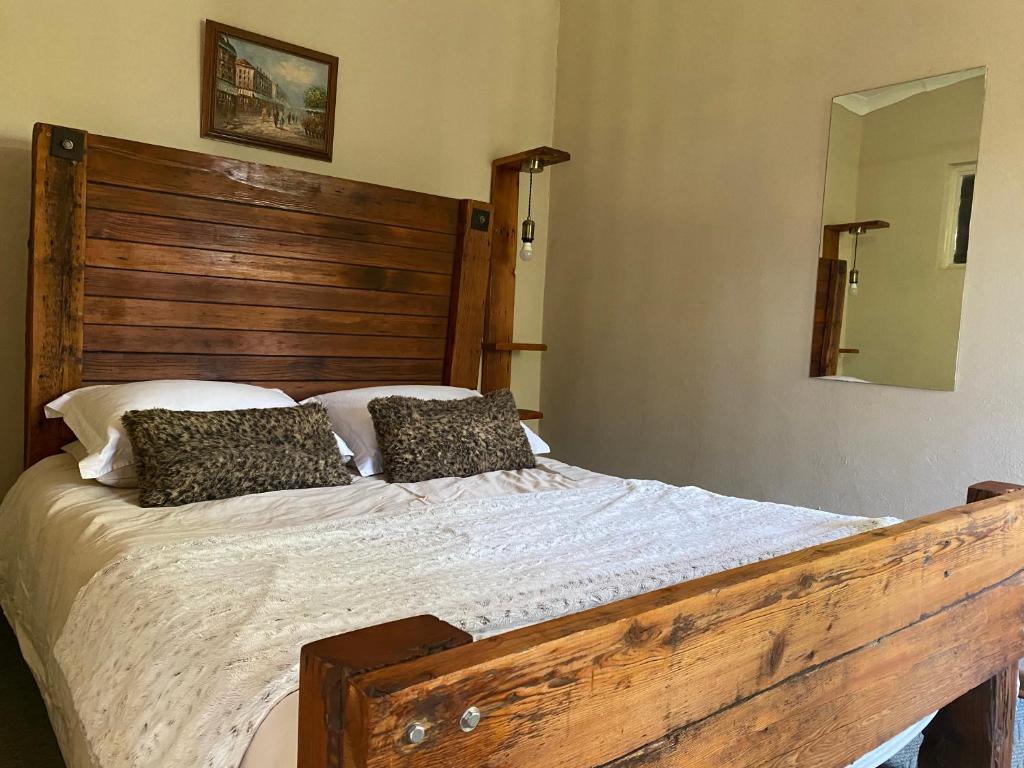 a bedroom with a large bed with a wooden headboard at Soetvlei Farm Cottage in Magaliesburg