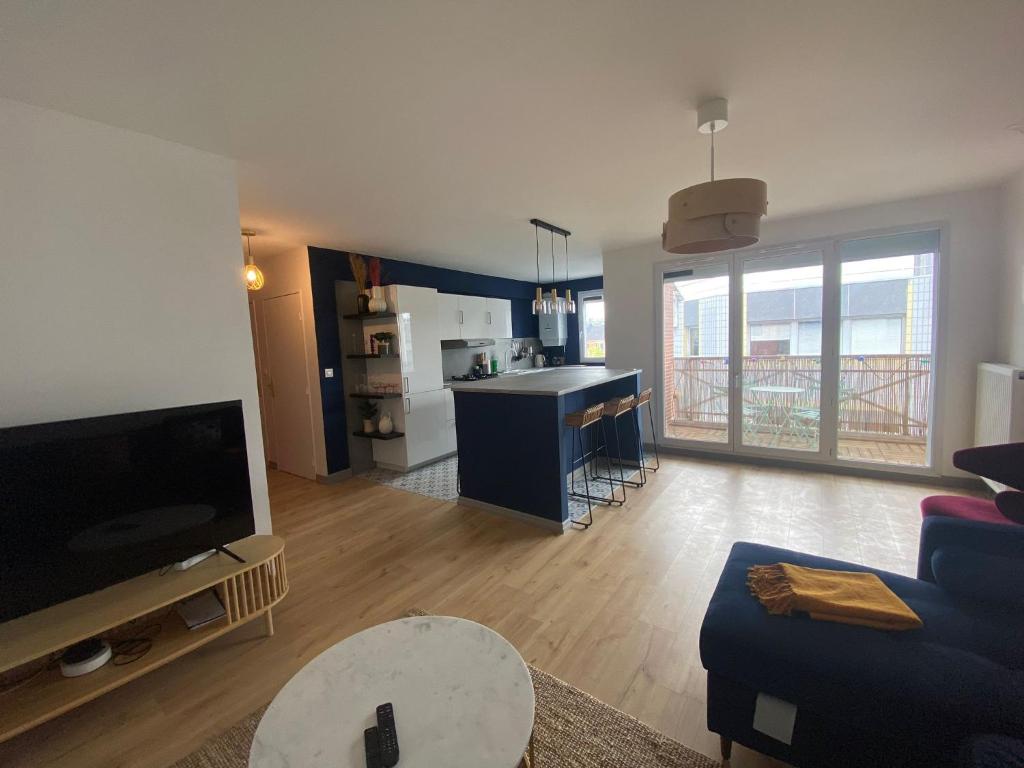 un salon avec un canapé bleu et une cuisine dans l'établissement L'appartement Eclat contemporain -310, à Rouen