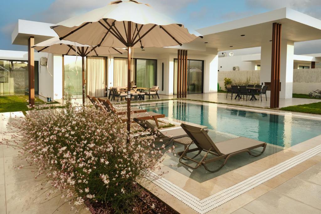 a pool with chairs and umbrellas in a house at Ashta Gold Suite in Fethiye