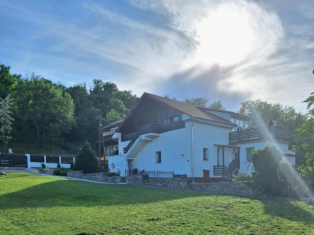 una casa blanca en un césped con el sol en el cielo en Holling apartman, en Fertőboz