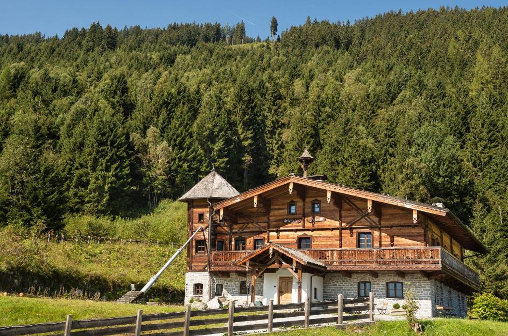 a large wooden house in the middle of a field at MONDI Schiefe Alm Gastein in Bad Gastein