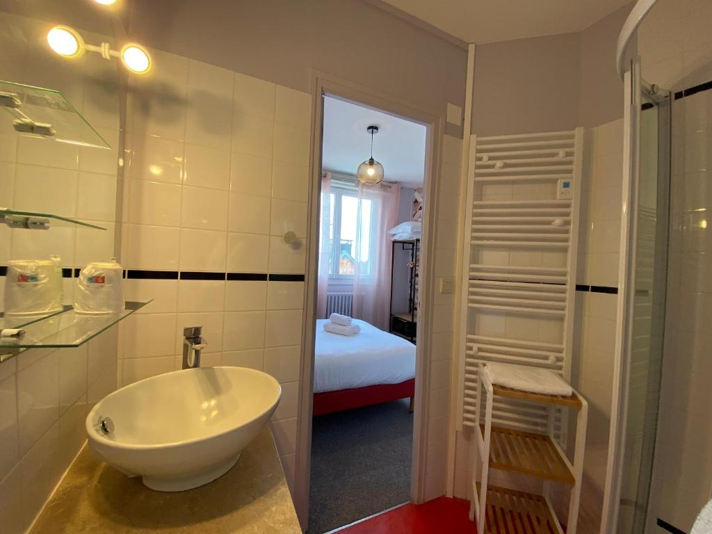 a bathroom with a tub and a sink and a bedroom at Hôtel du Musée in Granville