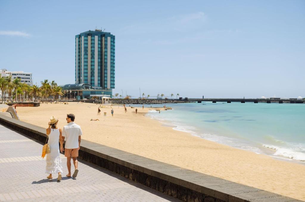 Una novia y un novio caminando por la playa en Arrecife Gran Hotel & Spa en Arrecife