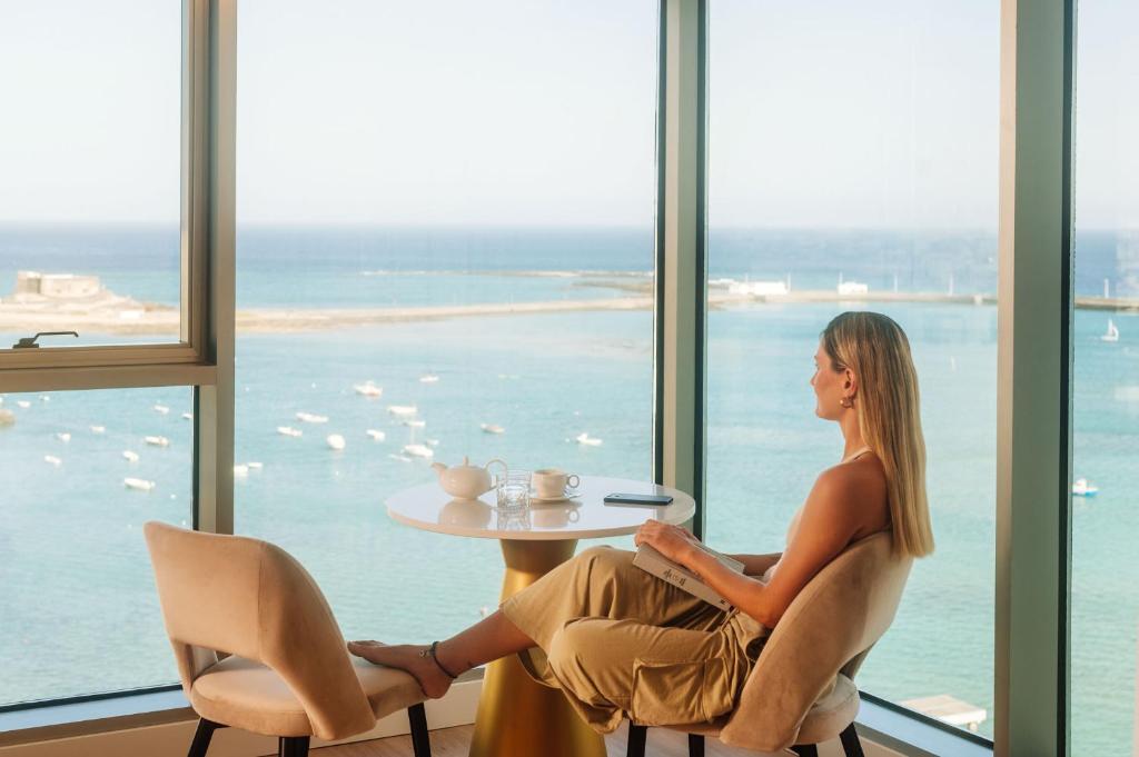 a woman sitting at a table in front of a window at Arrecife Gran Hotel & Spa in Arrecife