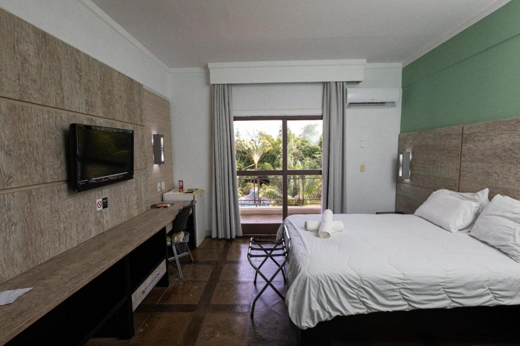 a hotel room with a bed and a window at ARAGUAIA HOTEL in Barra do Garças