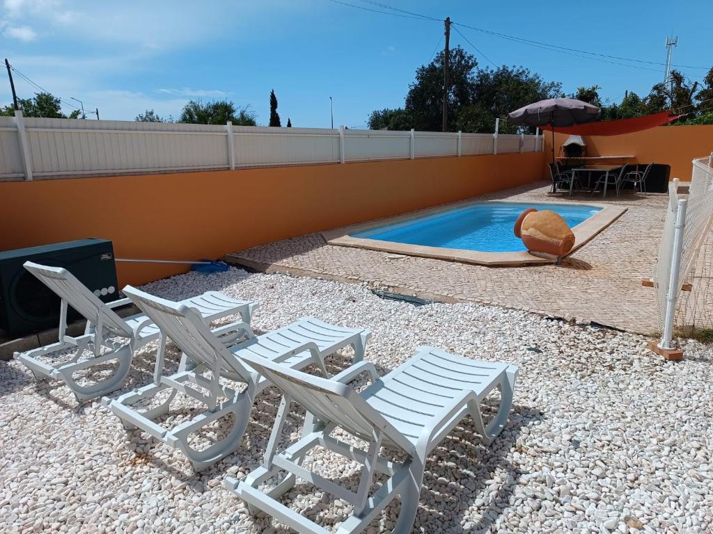 un groupe de chaises assises à côté d'une piscine dans l'établissement Holiday HouseV5 W/Pool & BBQ, à Albufeira