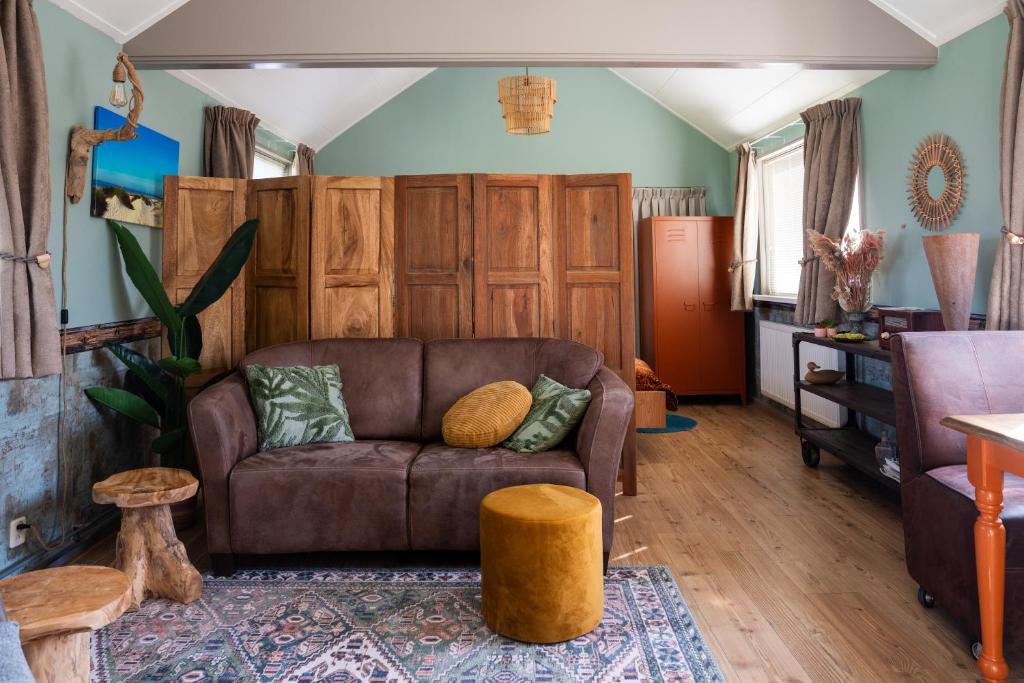 a living room with a brown couch and wooden cabinets at Het Zomerhuis in Egmond-Binnen