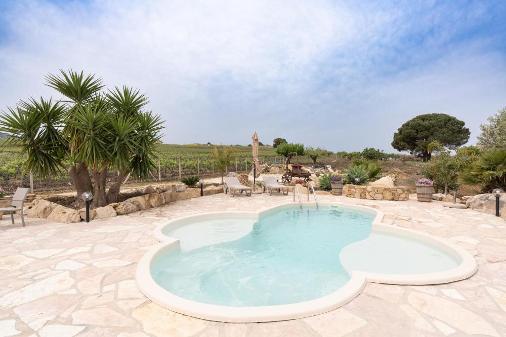a large swimming pool in a patio with palm trees at Villa Siciliana con piscina privata in Buseto Palizzolo