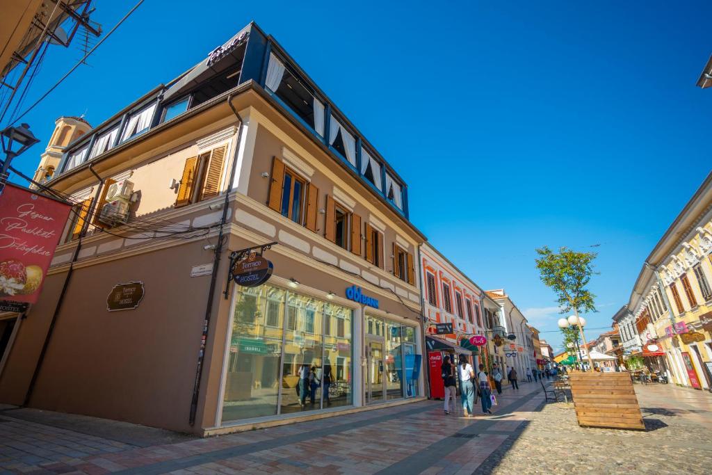 ein Gebäude auf einer Straße mit Leuten, die auf der Straße spazieren in der Unterkunft Terrace Hostel & Lounge Bar in Shkodra