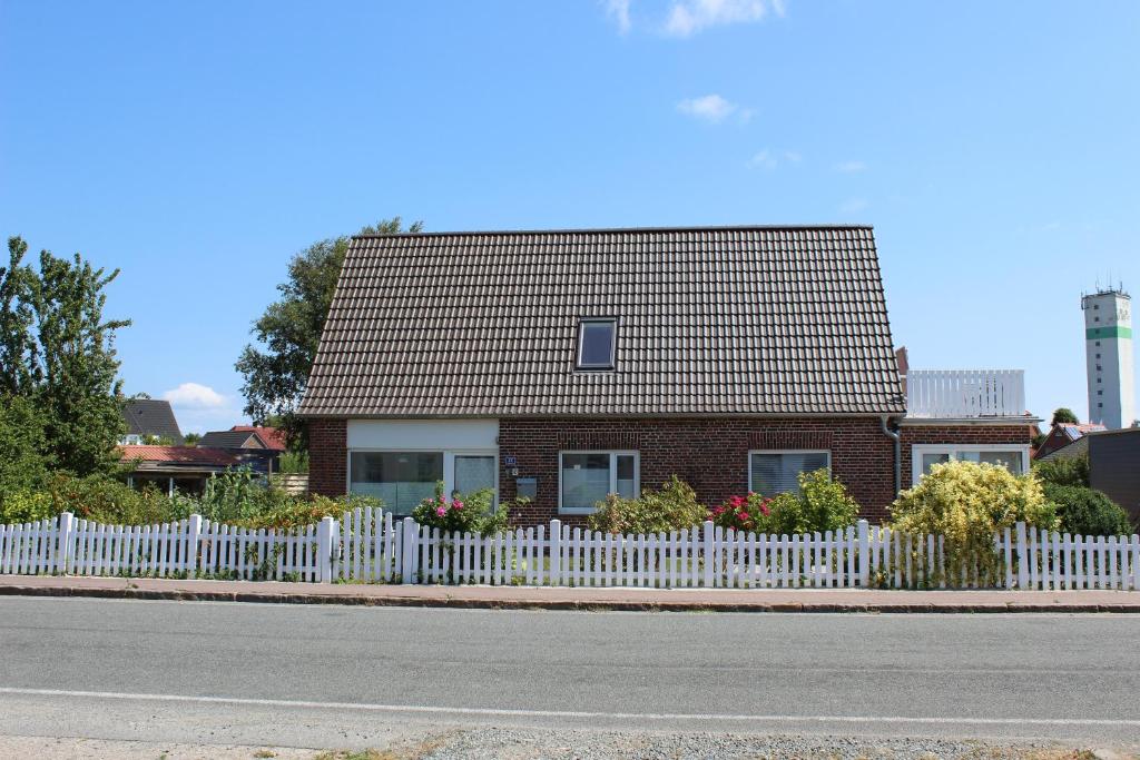 una casa de ladrillo con una valla blanca en Haushälfte am Süderhafen, en Nordstrand