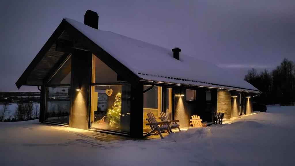 une maison dans la neige avec un arbre de Noël dans la fenêtre dans l'établissement Golsfjellet - new modern cabin with fantastic view, à Golsfjellet