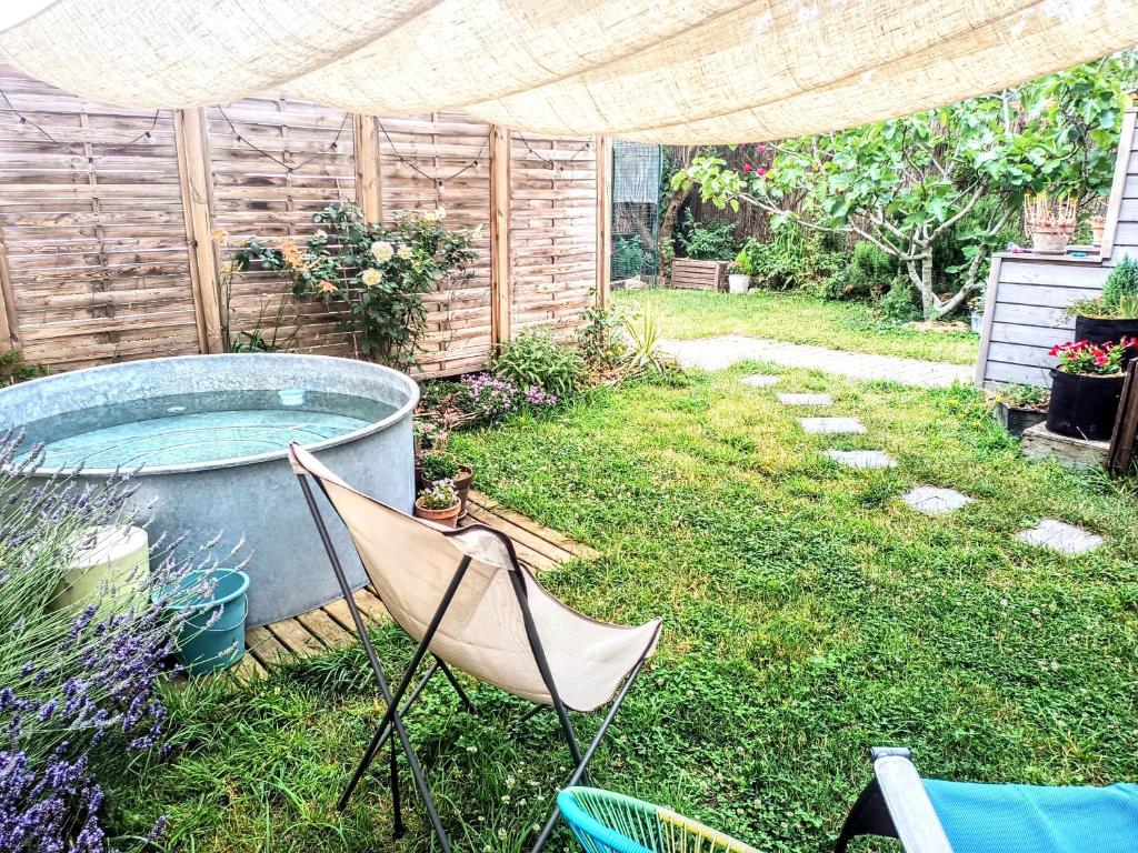 a yard with two chairs and a hot tub at La Fremille - Nid nature - Piscine & terrasse - 400m gare Paris in Saint-Cyr-lʼÉcole