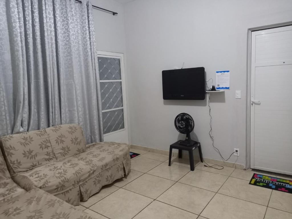 Casa 11 hóspedes Temporada em Ribeirão في ريبيراو بريتو: غرفة معيشة مع أريكة وتلفزيون بشاشة مسطحة