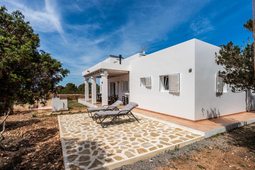 a white house with two chairs on a patio at Casa Es Vedrà in Cala Saona