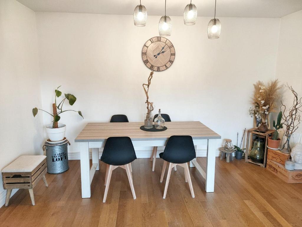 a dining room table with chairs and a clock on the wall at Maison de 2 chambres avec jardin clos et wifi a Vierzon in Vierzon