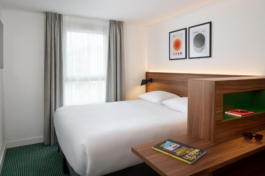 um quarto de hotel com uma cama grande e uma janela em Timhotel Nation em Paris